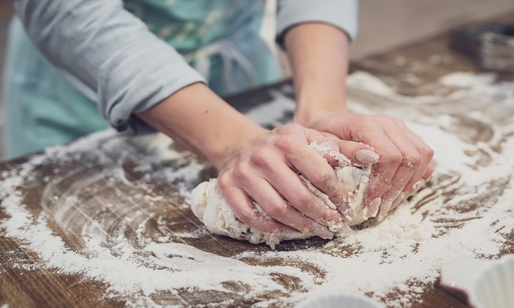 A woman kneading the homemade dough she is making in her luxury house's kitchen | Luxury Homes by Brittany Corporation