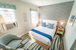 Wide angle shot of a small bedroom with unique and colorful patterns on the wall, the rug, and the bedsheets | Luxury Homes by Brittany Corporation