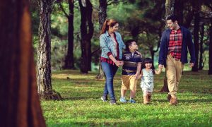 A young family of four enjoying a stroll through the lush green pine trees at Crosswinds Tagaytay | Luxury Homes by Brittany Corporation