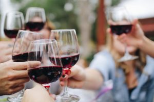 A group of white college friends in the backyard of their luxury home who are now young professionals celebrating an event by having a toast of red wine | Luxury Homes by Brittany Corporation