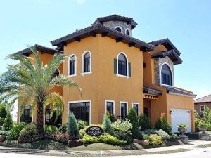 Tall orange Italian classic mansion with front garden and palm trees | Luxury Homes by Brittany Corporation