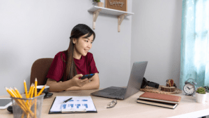 Young professional Asian girl working at her home office setup happily, with elements of her youthful personality showing in the furniture and decoration | Luxury Homes by Brittany Corporation