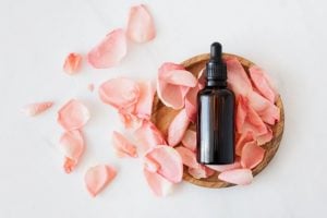 Black serum on glass bottle on top of pink rose petals, the best skin care tips for a luxury home spa experience - Luxury homes by Brittany