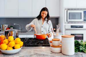 Girl cooking breakfast in the spacious kitchen of her luxury home, luxuries in the new normal | Luxury Homes by Brittany Corporation