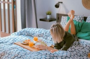 Woman laying down about to have her breakfast in bed in her luxury home at Brittany 