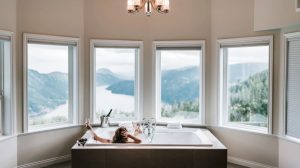 Woman practicing best skin care tips with a luxury home spa experience in a bathtub with a grand view at Brittany Corporation