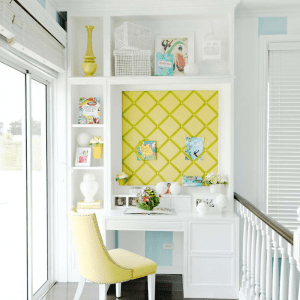 The unique architecture of a home office nook with a desk, comfortable chair, yellow wall board, and decorations | Luxury Homes by Brittany Corporation