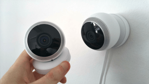 ight skinned hand installing two round home security cameras or CCTV that are color white and have built in mics | Luxury Homes by Brittany Corporation