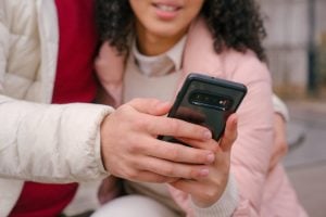 A young couple outside their luxury home using their phone as a sign of the digital transformation happening today | Luxury Homes by Brittany Corporation