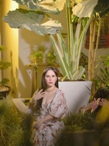 Elegantly dressed long black haired and fair skinned woman Jinkee Pacquaio, wife of Manny Pacquiao, in a living room surrounded by leafy green indoor expensive house plants of all sizes | Luxury Homes by Brittany Corporation