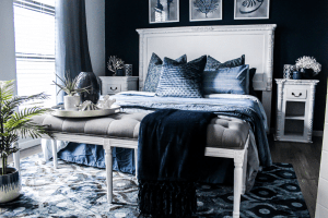 Blue themed bedroom with a queen size bed of comfortable sheets and pillows, on a patterned rug on the wooden floor perfect for fixing your sleeping habits | Luxury Homes by Brittany Corporation