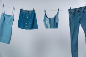 Dress, buttoned skirt, patchy crop top, and pants or jeans all made of denim material or cloth, all hung on a clothesline inside a white room | Luxury Homes by Brittany Corporation