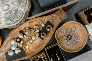 Stone jewelry of rings, bracelets, earrings, and necklaces, on display on thick wooden plates.