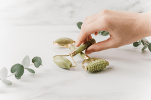  A hand getting two gua sha rollers on a marble surface which are part of a set of trendy new items | Luxury Homes by Brittany Corporation