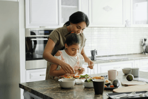 Middle Eastern mother helping child prepare breakfast in a white kitchen | Luxury Homes by Brittany Corporation