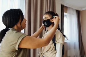 Mother putting facemask on daughter as they stay safe in their luxury home | Luxury Homes by Brittany Corporation