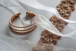 Rose gold choker necklace and bangles with rhinestones on a white surface, covered by tulle ribbons | Luxury Homes by Brittany Corporation