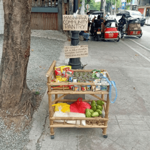A community pantry wooden stall containing vegetables, canned goods, bags of rice, hand sanitizers, instant coffee, and other packaged goods for free; for the benefit of the local community who are poor | Luxury Homes by Brittany Corporation