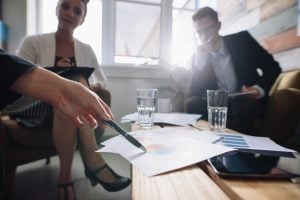 Shot of business people in a meeting at office, with woman pointing at charts. Corporate professional discussing financial growth of the company | Luxury Homes by Brittany Corporation