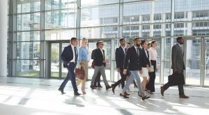 A group of multiracial real estate sales professionals walking together towards the same direction inside a modern building.