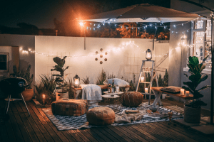 Outdoor porch chill cozy vibe setup with hanging fairy lights and boho furniture perfect for the rainy season | Luxury Homes by Brittany Corporation