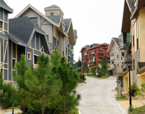 Neutral pastel colors Swiss quadrille houses and European homes lined up with healthy lush green pine trees, and a wide spacious paved road | luxury homes by brittany corporation