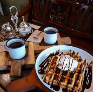 Two cups of freshly brewed coffee paired with a couple of waffle topped ice cream dish in a café shop | Luxury Homes by Brittany Corporation