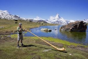 One of the most iconic sounds in Swiss-German music is the Alphorn as used by an Alphorn player with the Swiss Alps as the background. | Luxury Homes by Brittany Corporation