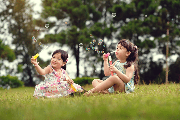 children blowing bubbles in front of a pine tree forest