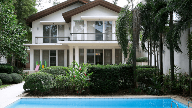 Elegant white and brown house with pillars, backyard garden, and swimming pool. | luxury homes by brittany corporation