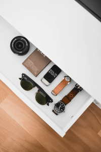 A drawer containing sunglasses, watches, and a camera lens | Luxury Homes by Brittany Corporation