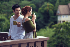 Man and woman drinkning coffee on a balcony as woman look out the view with green shawl | Luxury homes by brittany corporation