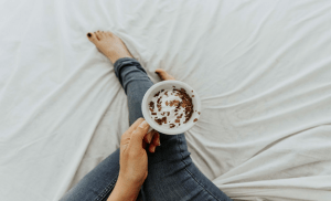 Holding a cup of hot chocolate while relaxing in bed is one of the simple but refreshing staycation activities | Luxury Homes by Brittany Corporation
