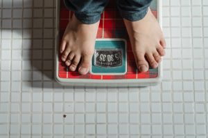 Person checking weight in a red and green weighing scale in thei cr of the luxury house and lot | luxury homes by Brittany Corporation