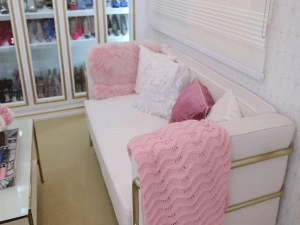 alk in closet with white sofa with cushion and golden elements.