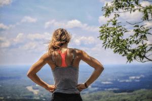 White woman taking in view after jogging on an elevated trail. Jogging requires you to increase your amount of drinking water | Luxury Homes by Brittany Corporation