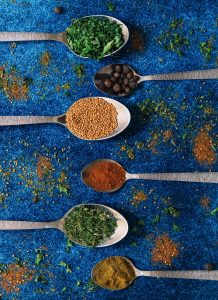 6 spices on silver spoons over a blue textured background | luxury home by brittany corporation