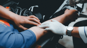 Doctor checking pulse of man's arm while on stretcher