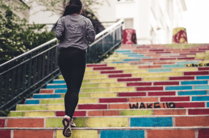 girl running up colorful stairs outdoors for fitness and health and to burn calories | luxury homes by brittany corporation