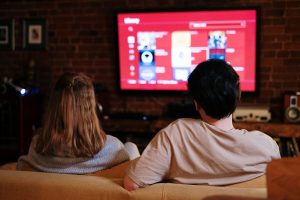 A couple of teenagers watching movies on TV in the living room as a pandemic response | luxury lifestyle and homes by brittany corporation