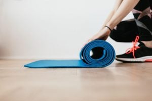 Sporty girl rolling yoga mat for exercise use as a pandemic response | luxury lifestyle and homes by brittany corporation