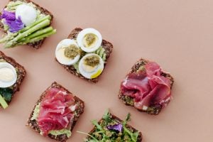 Avocado toast with various toppings on pink background | Luxury Homes by Brittany Corporation