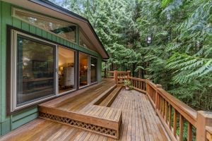 A landscape view of a hardwood house porch home features, surrounded by lush pine trees.