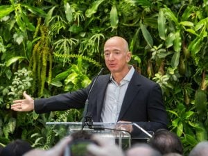 Jeff Bezos explaining the space race with a background of sustainable plants in a conference | luxury homes by brittany corporation