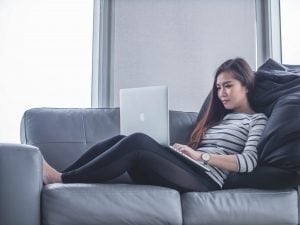 Woman sitting on sofa while using Macbook Pro at her luxury house and lot for sale in the Philippines - Brittany Corporation