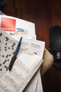 pen on newspaper crosswords on stack of magazines at home | luxury homes by brittany corporation