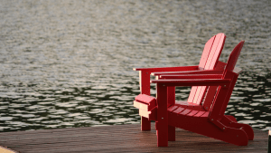 two retirement red wooden chairs benches on a wooden platform overlooking a lake for retirement places | luxury homes by brittany corporation