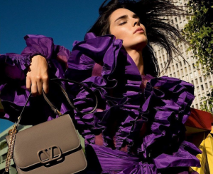 Brunette Lady wearing a purple ruffled blouse while holding a brown valentino bag | luxury homes by brittany corporation