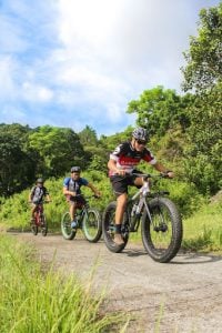 Three men riding a bicycle in Santa Rosa Luxury Communities | Luxury homes by brittany corporation.