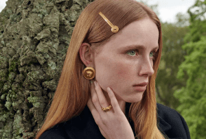 Irish-American Woman with red hair and green eyes in front of a tree bark | Luxury Homes by Brittany Corporation